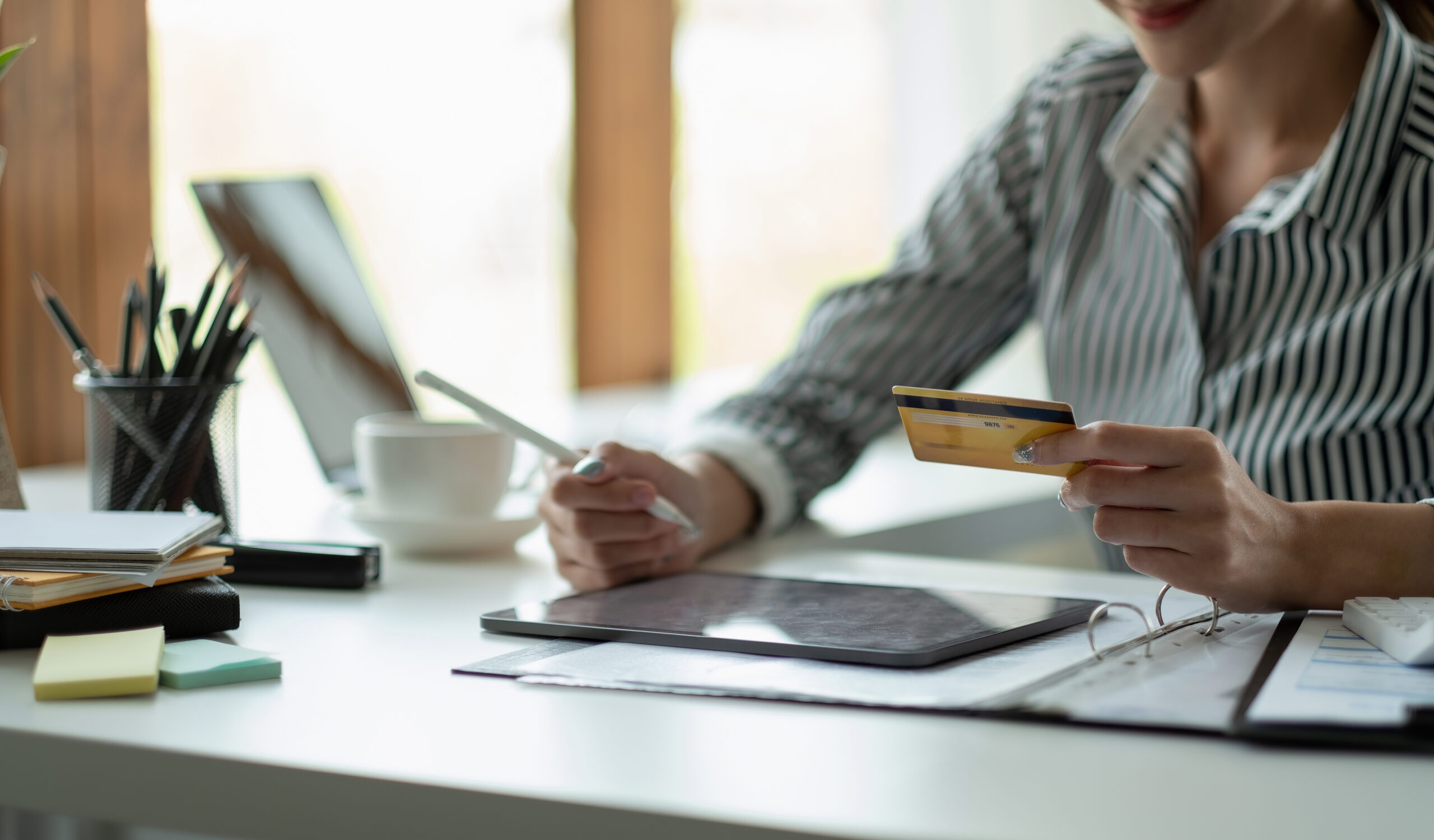 Kvinne som holder et kreditkort mens hun ser på en bunke regninger, symboliserer viktigheten av kredittscore.